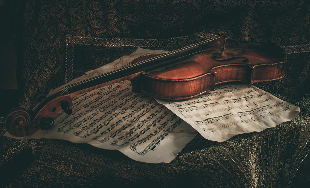 A violin atop a pile of sheet music